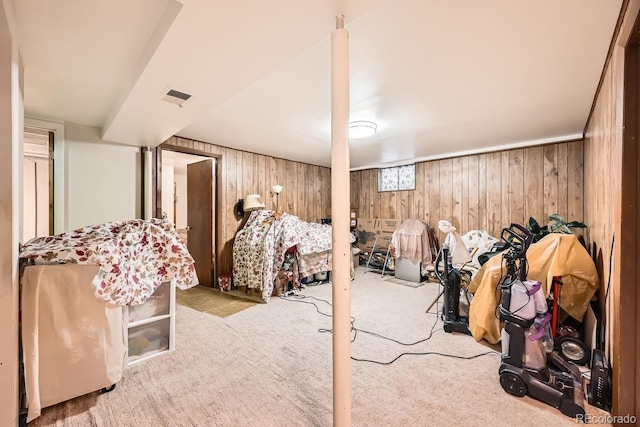 below grade area featuring wooden walls, visible vents, and light colored carpet