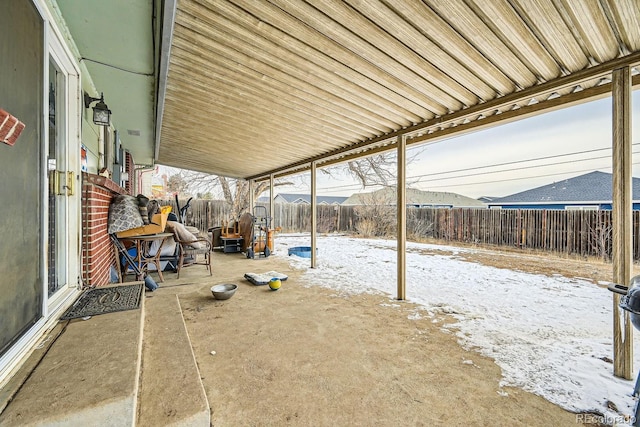 snow covered patio with a fenced backyard