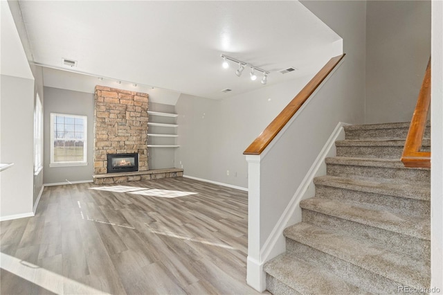 stairway featuring a fireplace, track lighting, and hardwood / wood-style flooring