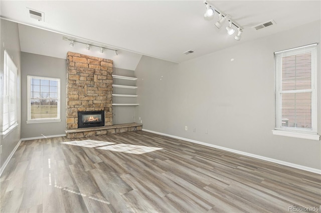 unfurnished living room with a fireplace, hardwood / wood-style floors, and track lighting