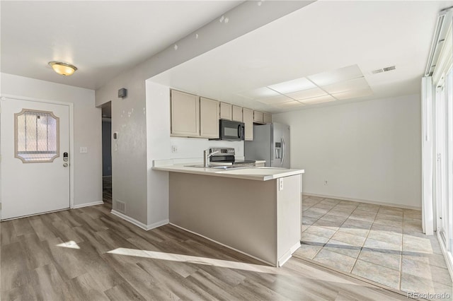 kitchen with plenty of natural light, kitchen peninsula, stainless steel appliances, and light hardwood / wood-style flooring