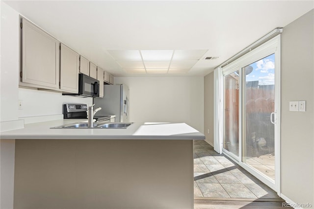 kitchen with kitchen peninsula, sink, light wood-type flooring, and stainless steel appliances