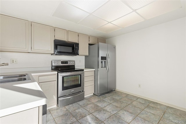 kitchen featuring light tile patterned floors, sink, appliances with stainless steel finishes, and cream cabinets