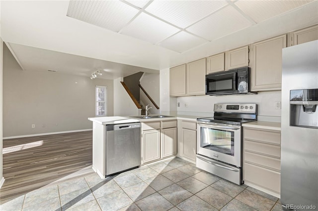 kitchen with sink, kitchen peninsula, cream cabinets, light hardwood / wood-style floors, and appliances with stainless steel finishes