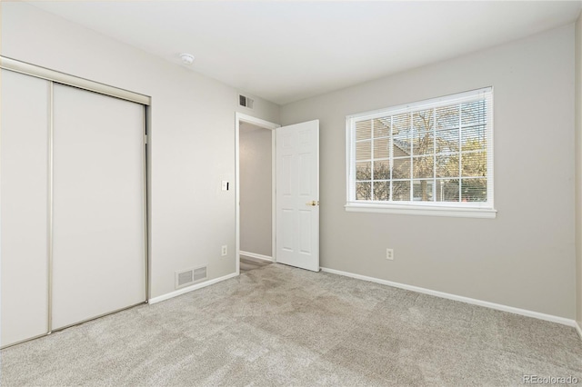 unfurnished bedroom with light carpet and a closet