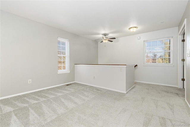 carpeted spare room featuring a wealth of natural light and ceiling fan