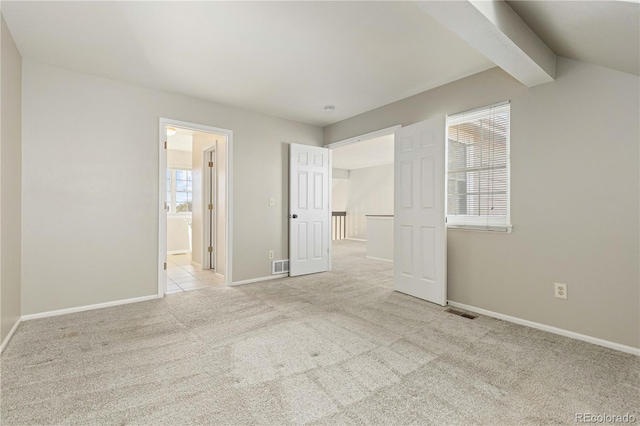 unfurnished bedroom with vaulted ceiling with beams, connected bathroom, light colored carpet, and multiple windows