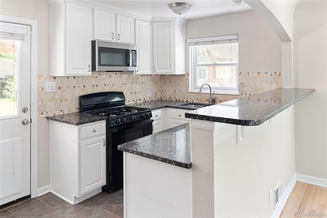 1856 S Monroe St, Denver, CO 80210 - kitchen with stainless steel microwave, gas stove, white cabinetry, a peninsula, and a breakfast bar area
