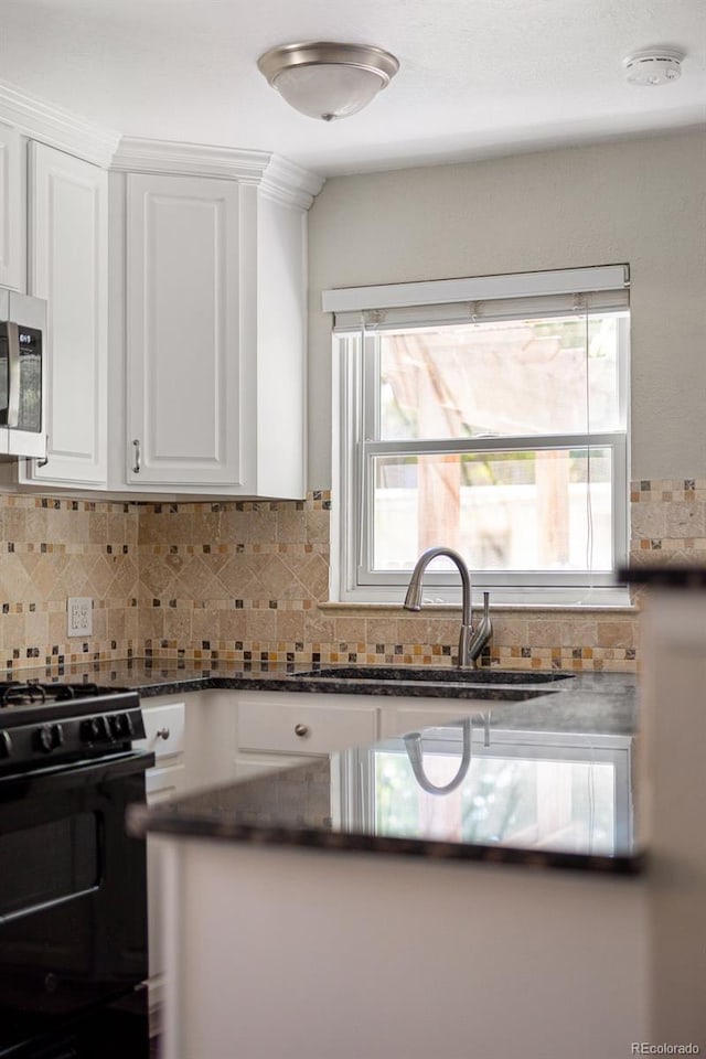 1856 S Monroe St, Denver, CO 80210 - kitchen with black gas stove, stainless steel microwave, white cabinets, tasteful backsplash, and dark stone counters