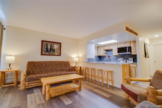 living area with a baseboard heating unit and wood finished floors