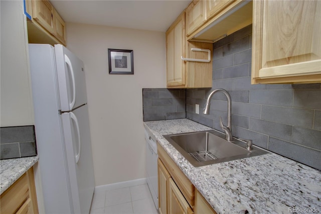 kitchen with light brown cabinetry, white appliances, a sink, and decorative backsplash