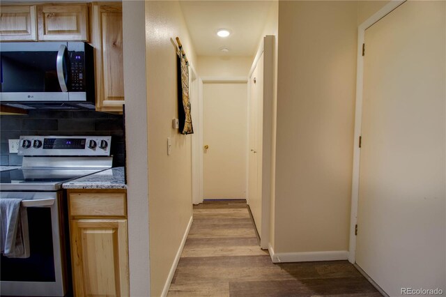 hallway featuring a barn door, baseboards, and wood finished floors