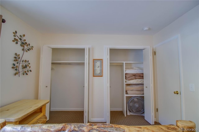 carpeted bedroom with two closets and baseboards