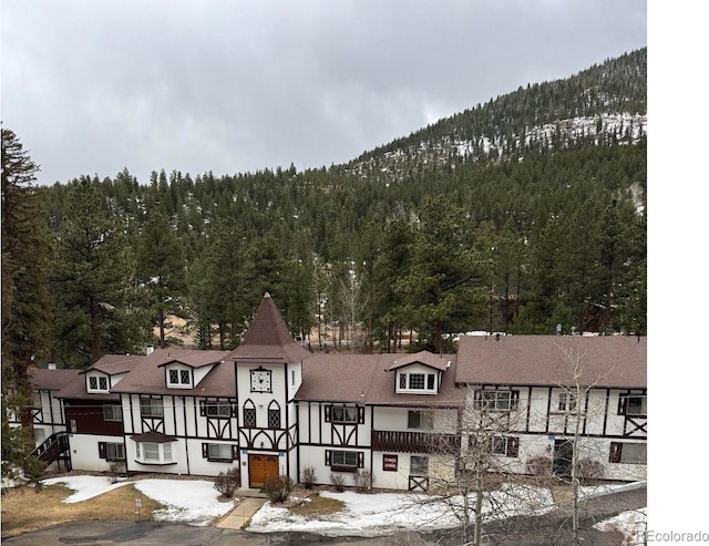 view of building exterior with a wooded view and a mountain view