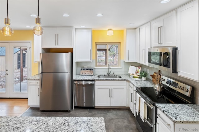 kitchen featuring white cabinetry, sink, french doors, stainless steel appliances, and pendant lighting