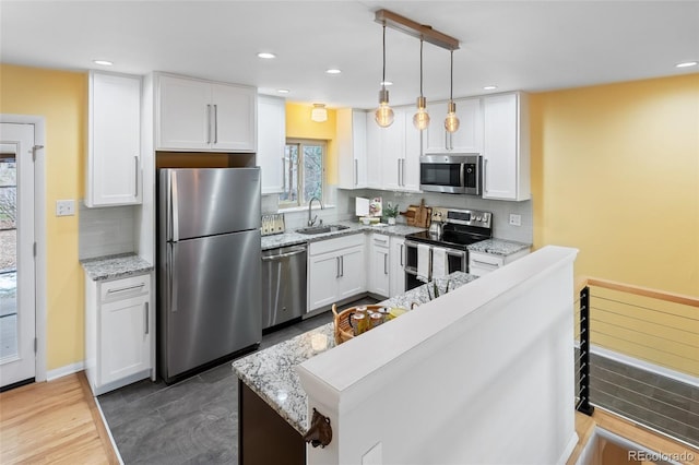 kitchen featuring pendant lighting, white cabinets, sink, light stone countertops, and stainless steel appliances