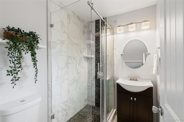 bathroom featuring vanity, toilet, and a shower with shower door