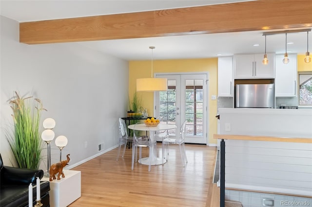 kitchen featuring white cabinets, decorative light fixtures, plenty of natural light, and stainless steel refrigerator