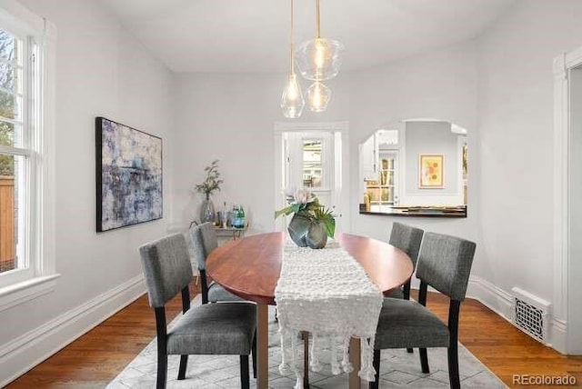 dining area featuring hardwood / wood-style floors, vaulted ceiling, and plenty of natural light