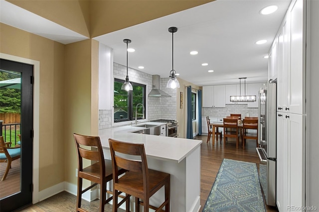 23 Honey Locust, Littleton, CO 80127 - kitchen with high quality appliances, tasteful backsplash, wall chimney range hood, light countertops, and white cabinetry