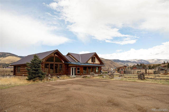 cabin featuring log exterior, a mountain view, metal roof, fence, and covered porch