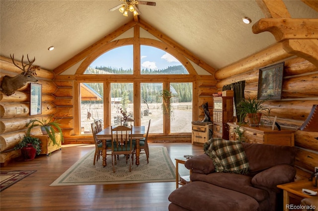living area with a textured ceiling, vaulted ceiling, log walls, a ceiling fan, and hardwood / wood-style flooring