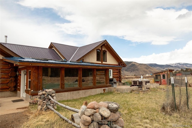 back of property featuring log exterior, a mountain view, and metal roof