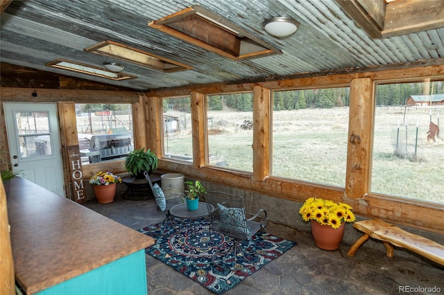 sunroom / solarium featuring plenty of natural light, a skylight, and stone finish floors