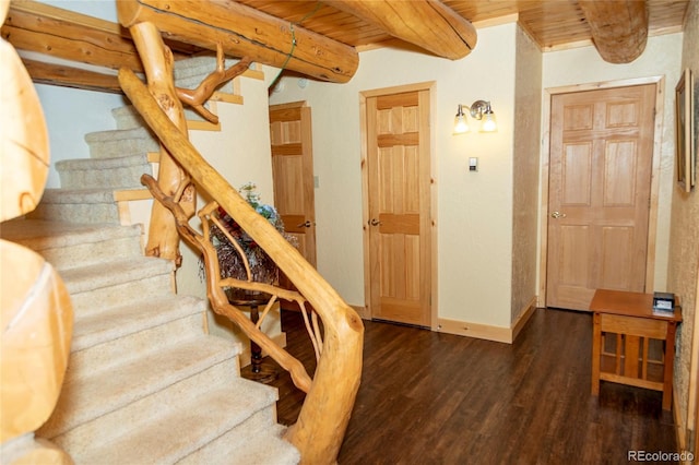 stairway with wood finished floors, beamed ceiling, baseboards, and wooden ceiling