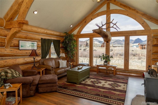 living room with a mountain view, rustic walls, wood finished floors, and high vaulted ceiling