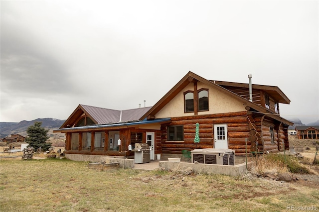 back of house featuring log exterior, a mountain view, a patio area, and metal roof
