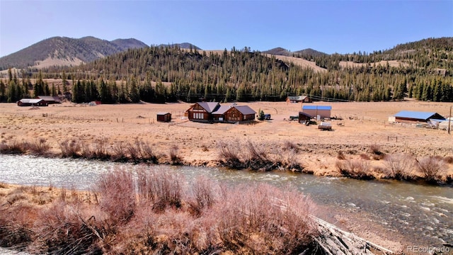 view of mountain backdrop with a heavily wooded area and rural landscape