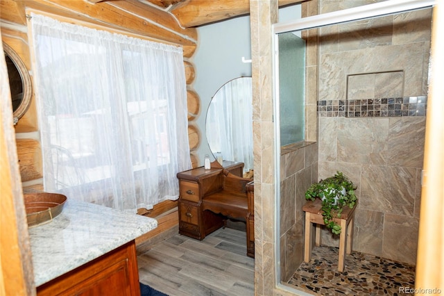 full bathroom with a tile shower, vanity, and wood finished floors