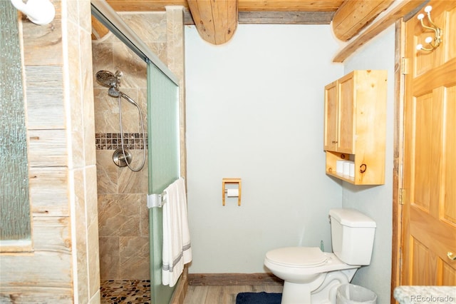 bathroom with a stall shower, toilet, beamed ceiling, wood finished floors, and baseboards