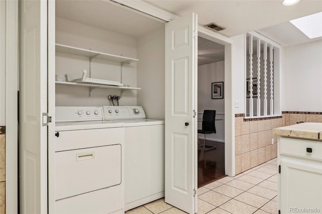 laundry area featuring separate washer and dryer, light tile patterned floors, and tile walls