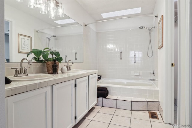 bathroom featuring tile patterned flooring, vanity, a skylight, and tiled shower / bath