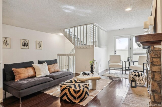 living room featuring stairway, baseboards, a textured ceiling, and wood finished floors