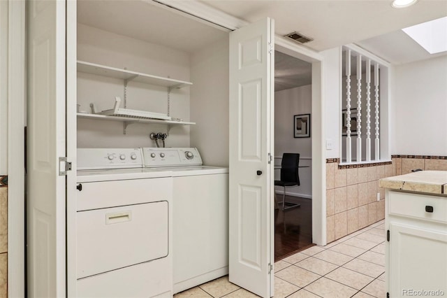laundry area with washing machine and clothes dryer, visible vents, light tile patterned floors, laundry area, and tile walls