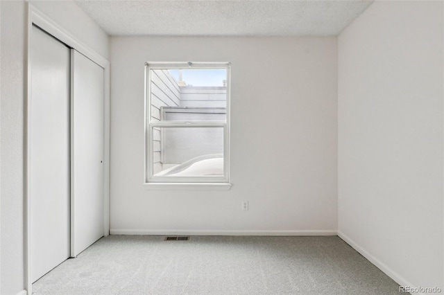 unfurnished bedroom with visible vents, baseboards, carpet flooring, a closet, and a textured ceiling