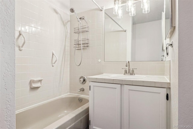 full bath featuring vanity,  shower combination, and a textured wall
