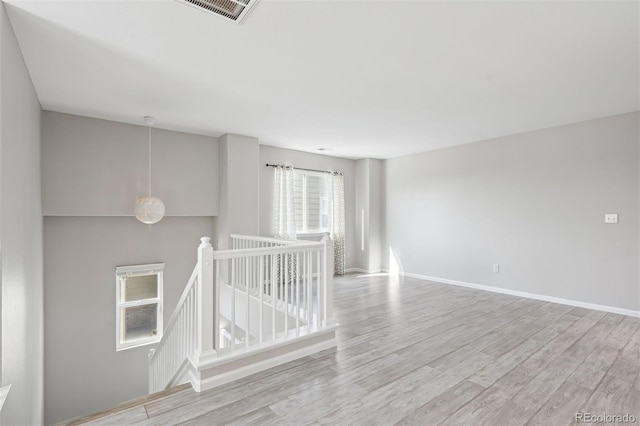 empty room with visible vents, light wood-style flooring, and baseboards