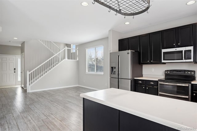 kitchen with light wood finished floors, dark cabinetry, light countertops, double oven range, and stainless steel fridge with ice dispenser