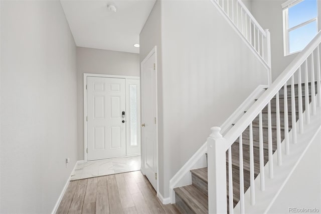 entryway with stairway, wood finished floors, and baseboards