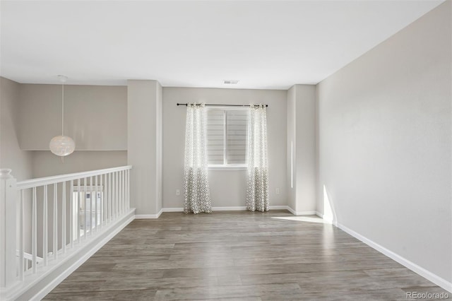 empty room with visible vents, baseboards, and wood finished floors