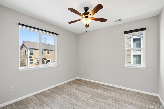 unfurnished room with a ceiling fan, visible vents, light wood finished floors, and baseboards