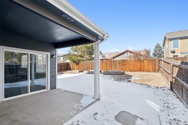 snow covered patio featuring a fenced backyard