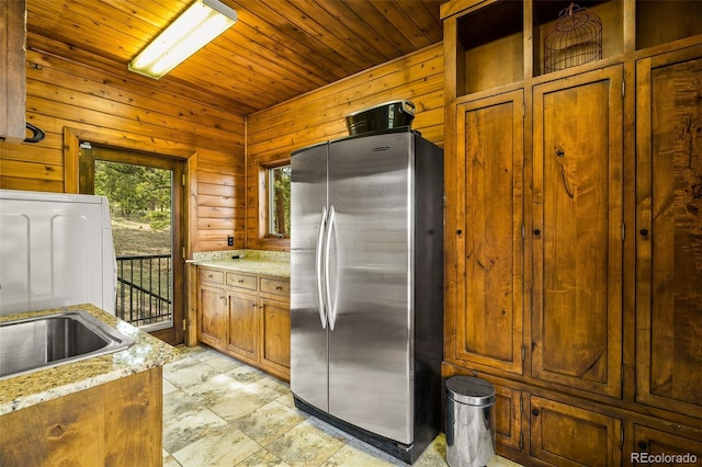 32806 Lakeside Dr, Buena Vista, CO 81211 - kitchen with freestanding refrigerator, brown cabinetry, wood ceiling, wooden walls, and light stone counters
