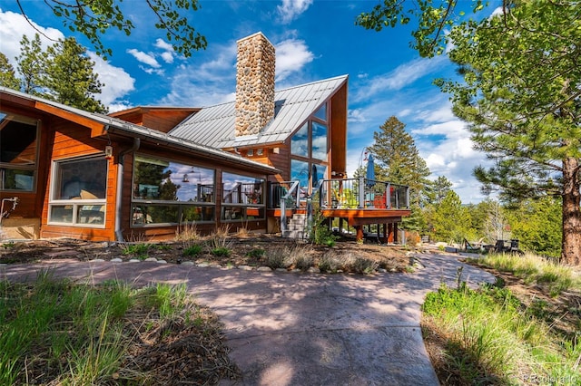 32806 Lakeside Dr, Buena Vista, CO 81211 - rear view of house featuring a chimney, a standing seam roof, a wooden deck, and a metal roof