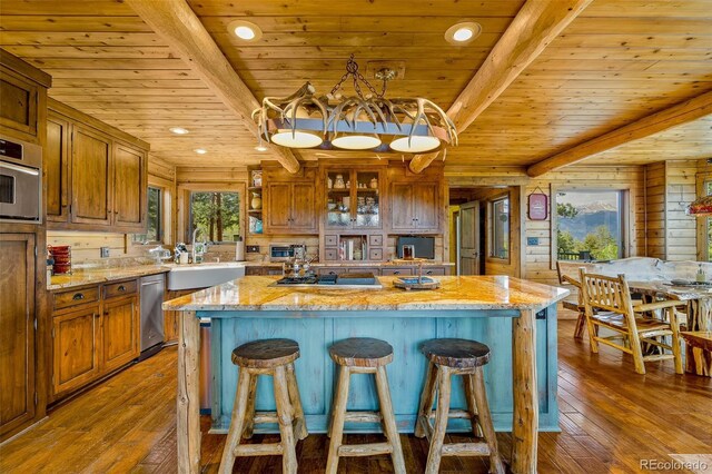 32806 Lakeside Dr, Buena Vista, CO 81211 - kitchen with a wood ceiling with exposed beams, light wood-style flooring, brown cabinets, a kitchen bar, and appliances with stainless steel finishes