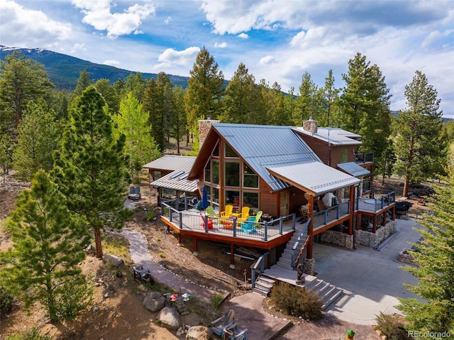 32806 Lakeside Dr, Buena Vista, CO 81211 - rear view of house with a chimney, a deck, a forest view, a standing seam roof, and stairs